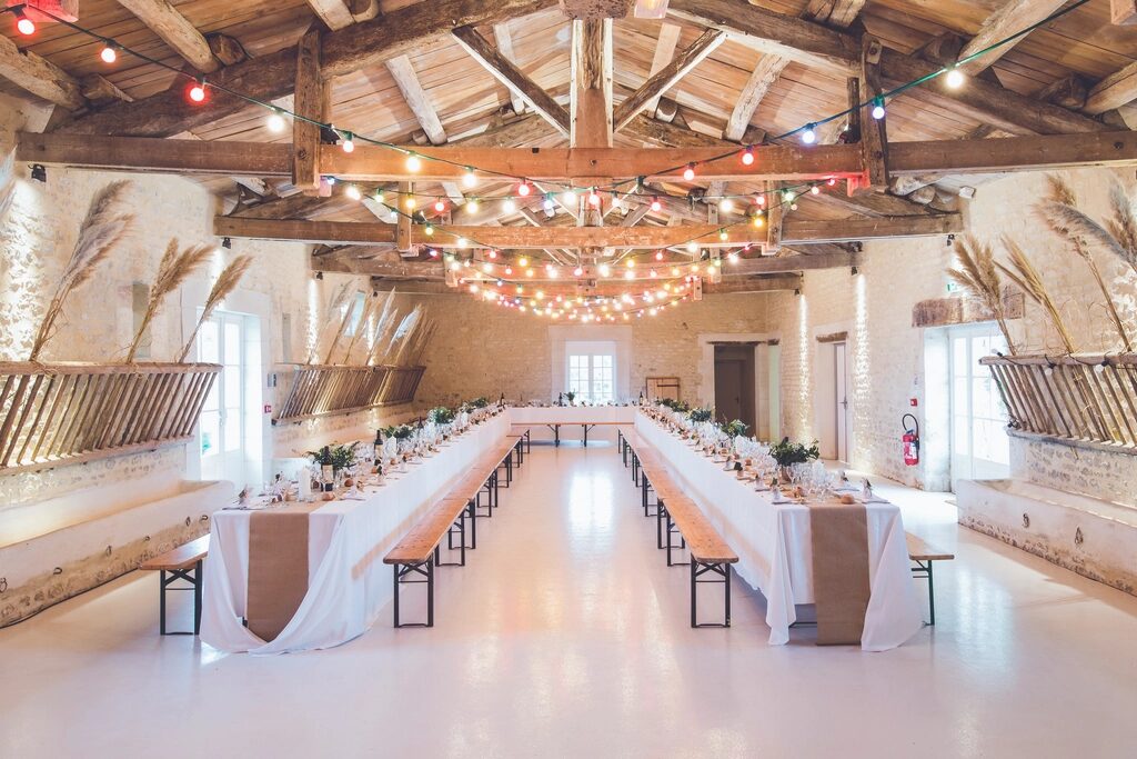 A beamed event hall set with long tables under string lights